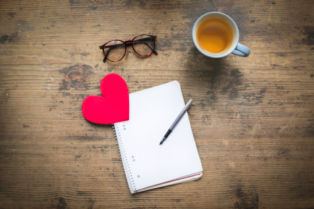 Valentines Day | note pad, heart, pair od glasses and a cup of tea on a table