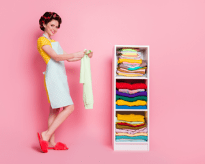Woman with hair in rollers and wearing and apron folding clothes | Spring Cleaning